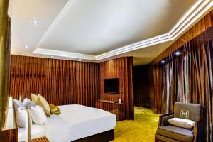 马六甲莫蒂酒店的一间卧室配有一张床、一把椅子和电视