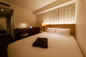 福冈HOTEL FORZA HAKATA-GUCHI的酒店客房,配有一张带枕头的床