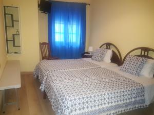 波尔图Caldeira Guest House的一间卧室设有两张床,窗户配有蓝色窗帘