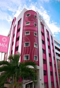 比亚埃尔莫萨Mia City Villahermosa的前面有棕榈树的粉红色建筑