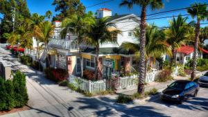 圣徒皮特海滩Coconut Inn Pass-a-Grille Beach的一条街道前的白色房子,种有棕榈树