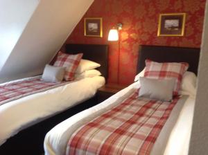 因弗内斯Royston Guest House Inverness的红色墙壁客房的两张床