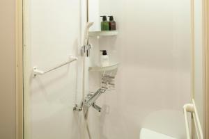 金泽日本金泽胶囊宾馆的白色的浴室设有水槽和淋浴。