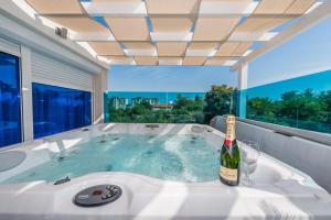 扎达尔莫雷别墅豪华公寓的热水浴池,配有一瓶葡萄酒和一杯