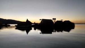 普诺Uros Suyawi Titicaca Lodge的日落时分坐在水中的一群船