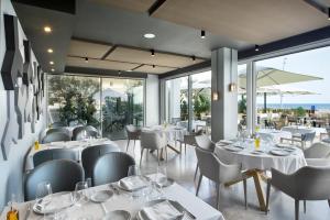 卡斯特尔德费尔斯多纳4*高级精品酒店的餐厅设有白色的桌椅和窗户。