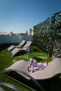 马拉加Holidays2Malaga Suites的坐在屋顶上草上的一组椅子