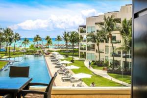普拉亚卡门The Elements Oceanfront & Beachside Condo Hotel的享有带游泳池和棕榈树的度假村的景致