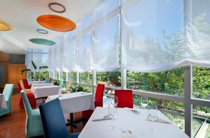 温哥华艾姆巴克温哥华钻石度假村的餐厅设有白色桌子和红色椅子以及大窗户