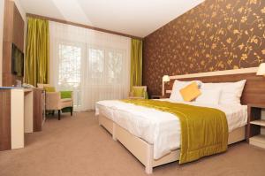 栋博堡Hotel Európa Gunaras的一间卧室配有一张带黄色毯子的大床
