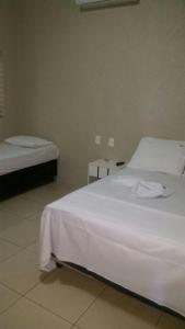 阿拉瓜伊纳Hotel Boiadeiro的一间卧室配有两张带白色床单的床