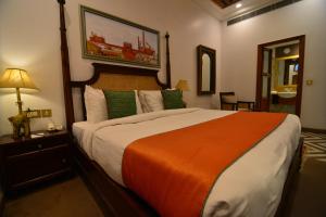 新德里Haveli Dharampura - UNESCO awarded Boutique Heritage Hotel的一间卧室配有一张带橙色毯子的大床