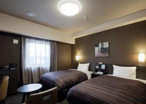 宇部宇部路特酒店的酒店客房设有两张床和一张桌子。