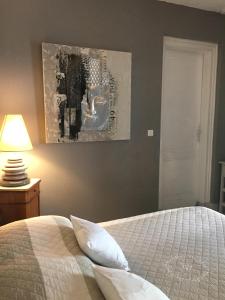 阿卡雄La Maison de Lilly的卧室配有一张床,墙上挂有绘画作品