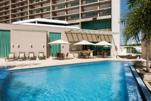 戈亚尼亚K酒店 的一座带桌子和遮阳伞的大楼前的游泳池