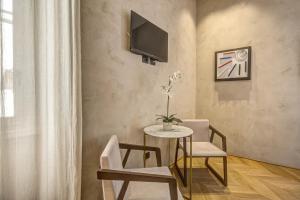 罗马G55设计酒店的客厅配有桌子、两把椅子和电视