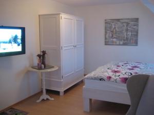 比苏姆Ferienhaus Wattenhus的一间卧室配有一张床、一个橱柜和一台电视