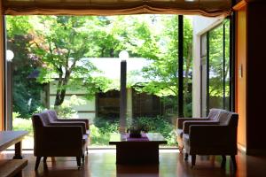 木曾町宿驹汤日式旅馆的配有大窗户的客房内配有两把椅子和一张桌子