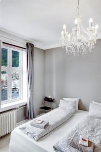 卑尔根布吕根美景公寓的一间白色卧室,配有两张床和吊灯