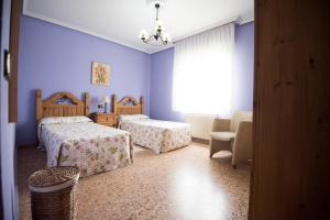 卢安科Maria la Carbayeda的一间卧室设有两张床、一把椅子和一个窗户。