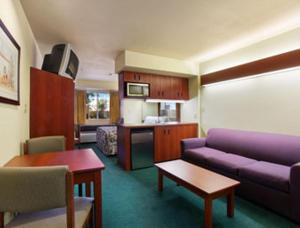 Wellton韦尔顿温德姆麦克罗特尔套房酒店的一间带紫色沙发的客厅和一间厨房