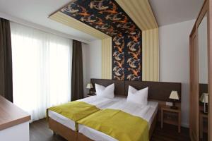 罗斯托克幻娜酒店的一间卧室配有一张带黄色毯子的大床