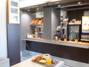 图尔B&B HOTEL Tours Nord 1 Val de Loire的面包柜台,上面放着一盘糕点和橙汁
