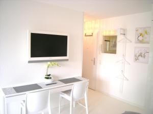 科隆A公寓的一间设有白色书桌的房间,墙上有电视