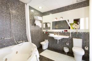 格拉纳达Hotel Carlos V的带浴缸、卫生间和盥洗盆的浴室