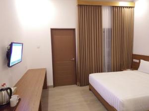 日惹Java Village Resort by HOMEE Yogyakarta的一间卧室配有一张床、一台电视和一扇门