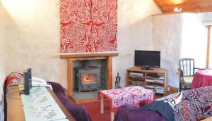 LuibGlas Bheinn Cottage的客厅设有壁炉和电视。