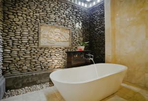 乌布Sri Ratih Cottages, CHSE Certified的带浴缸的浴室和石墙