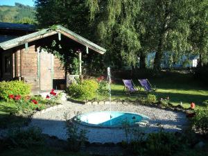 卡普伦Landhaus Griesser的庭院里的一个小游泳池,配有两把紫色椅子