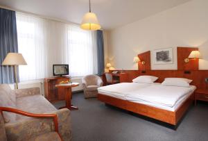 哥廷根汉诺威斯塔德特酒店的一间卧室配有一张床、一张沙发和一把椅子