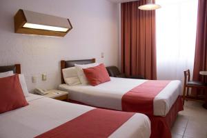 夸察夸尔科斯Hotel Enriquez的酒店客房带两张红色和白色的床单