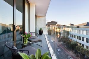 悉尼波坦尼克公寓式酒店的阳台配有桌椅,享有城市美景。