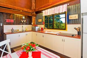 谭伯连山云山庄园负鼠山林小屋的厨房配有白色橱柜和鲜花桌