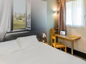 洛尔蒙B&B HOTEL Bordeaux Lormont的一间卧室配有一张床、一张书桌和一个窗户。