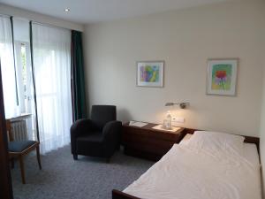 巴特拉尔Landhotel Ridder的配有一张床和一把椅子的酒店客房