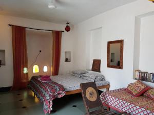 乌代浦银月哈维公寓的一间卧室配有两张床、一把椅子和镜子