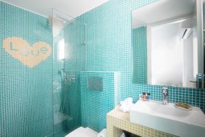 帕罗奇亚Acqua Vatos Paros Hotel的浴室设有蓝色瓷砖墙壁、水槽和镜子