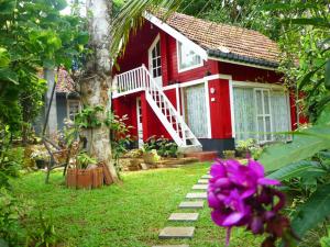 康提康提天堂小屋乡村民宿的红房子,有一棵树和一朵紫色的花