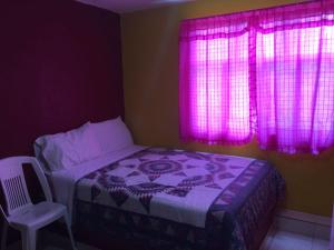希利特拉Hotel Economico的一间卧室配有一张床、粉红色窗帘和椅子
