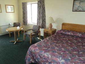 尼亚加拉瀑布Oasis Motel by The Falls的酒店客房带一张床、一张桌子和椅子