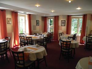 阿瓦隆Cit'Hotel Avallon Vauban的一间配备有桌椅和红色窗帘的用餐室