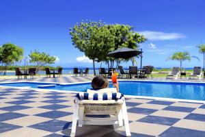 劳托卡尼拉海滩度假旅舍的坐在椅子上,在游泳池边拿着雨伞的人