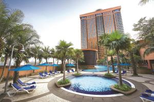 吉隆坡吉隆坡成功时代广场酒店的一座带椅子和棕榈树的游泳池以及一座高大的建筑