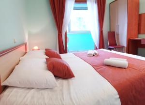 波梅纳波梅纳旅馆的一张配有红色和白色枕头的大床和窗户