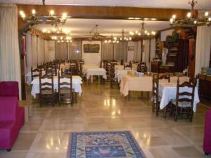 努斯杜亚尼酒店的用餐室配有白色的桌椅和灯光