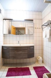 阿布特瑙豪斯奥贝拉斯拉克酒店的浴室设有水槽、镜子和粉红色地毯。
